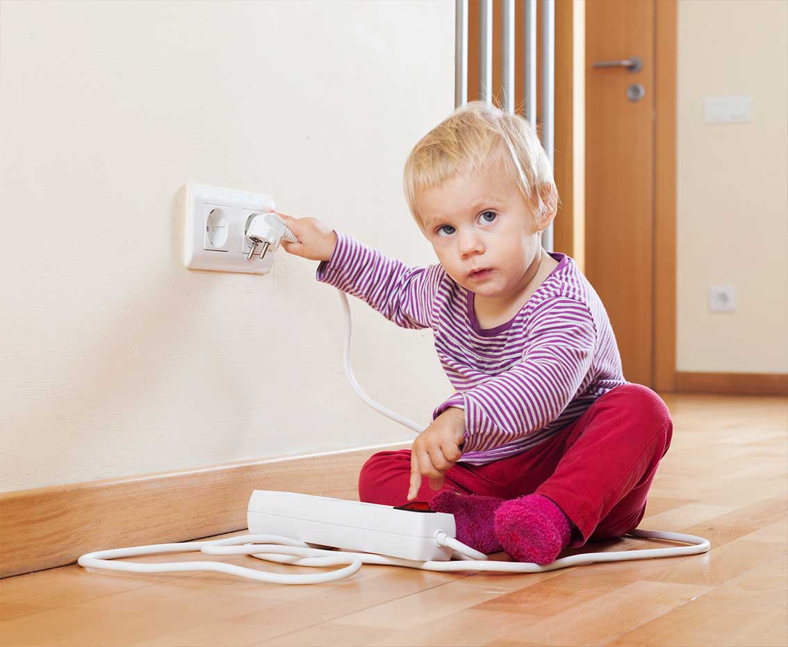 baby playing with electronic outlet with plug
